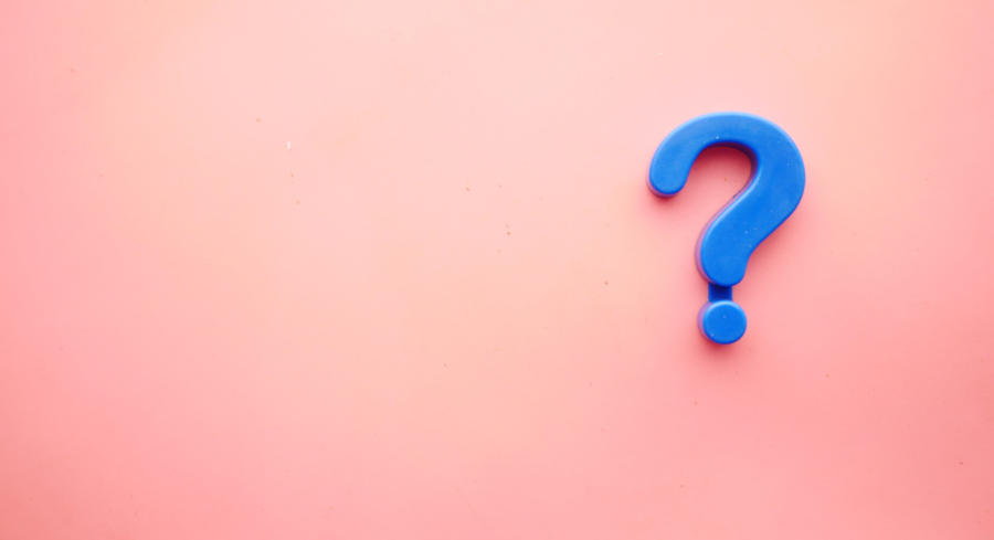 A blue magnet question mark on a pink wall background